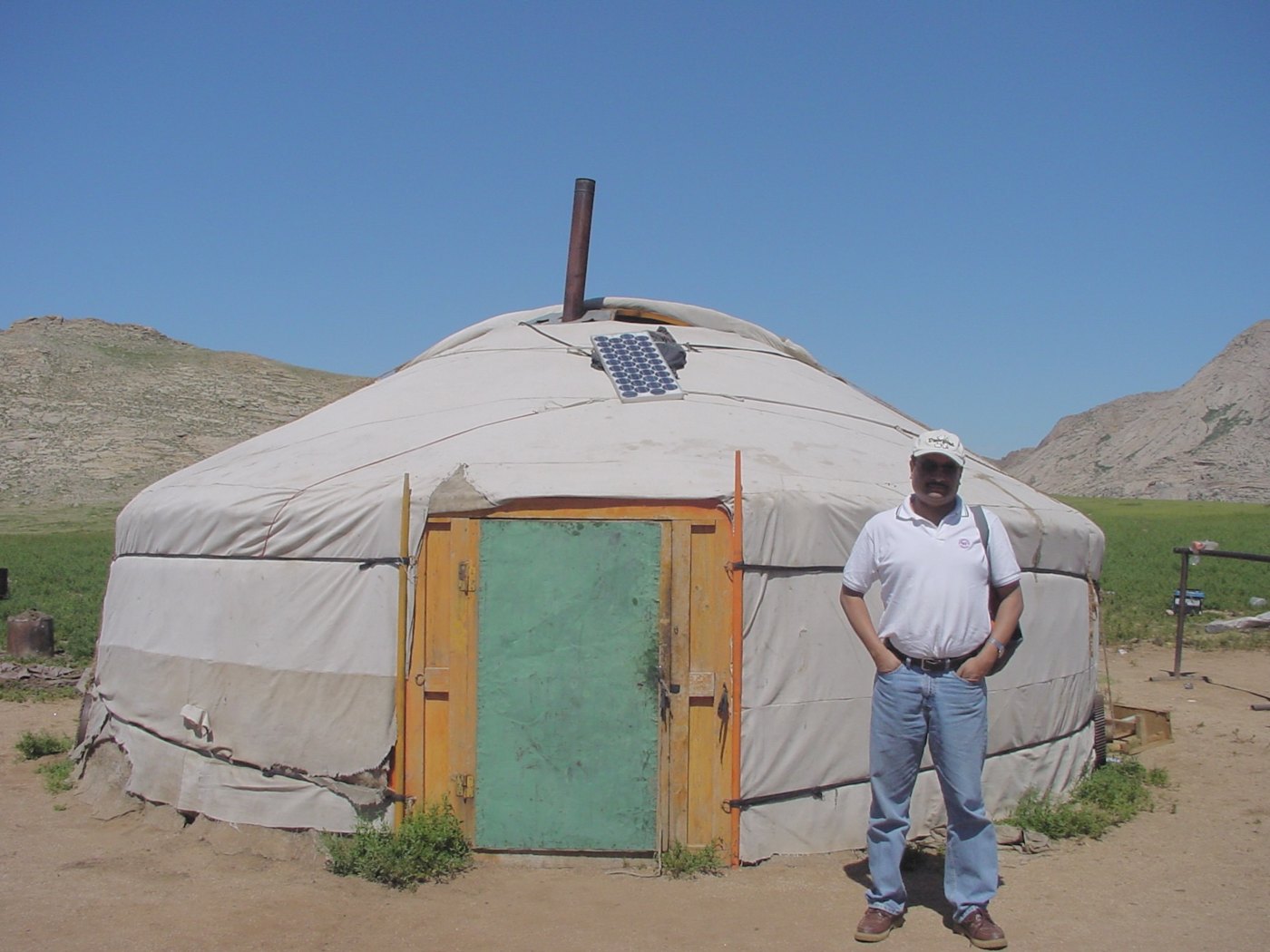 A Mongolian ger with a solar panel mounted on its roof, Sohail Hasnie standing alongside